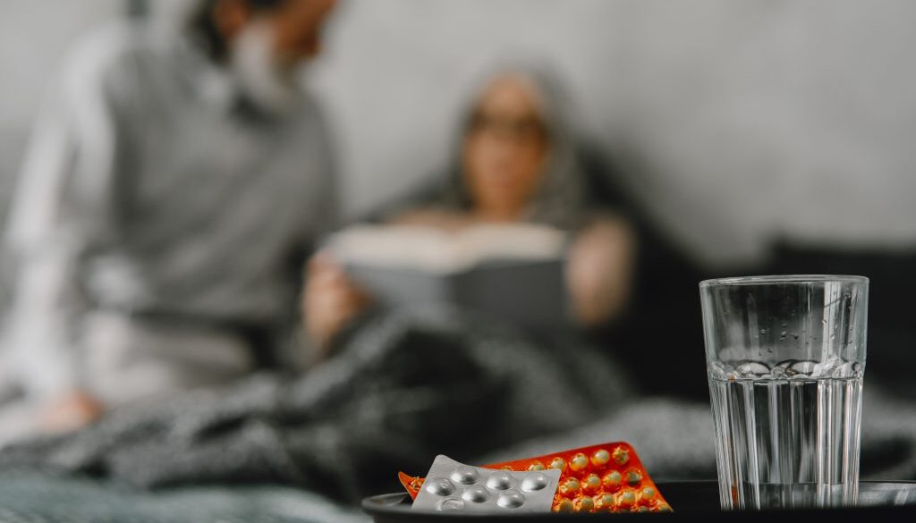 Pills and glass and senior couple on background